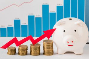 Lợn đất tiết kiệm và các chồng tiền xu tăng dần trước biểu đồ tăng trưởng tài chính